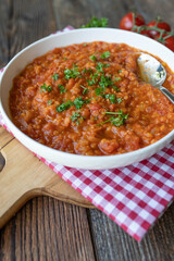 Vegan tomato soup with red lentils. Delicious healthy food. Served ready to eat on a plate on wooden table background.