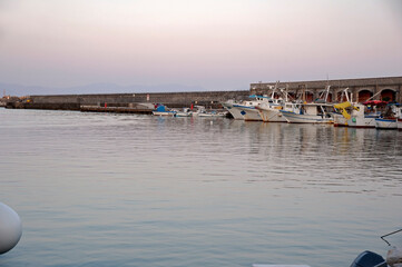 Vessels and some trawlers in the port along the quay at dusk. Marina di Camerota bay, Salerno,...