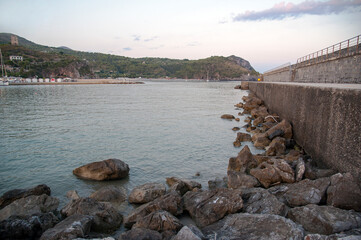 Terminal part of the concrete wharf with the entrance of the harbor at sunset. Marina di Camerota...