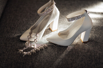 A pair of white shoes with a silver chain and a pair of earrings