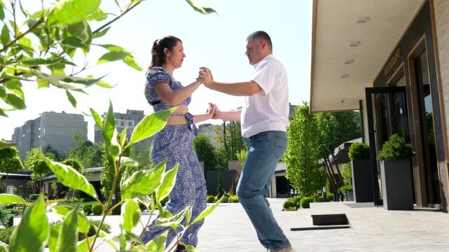 Urban mixed race couple dancing in classical public place. People dancing salsa and bachata in outdoor cafe