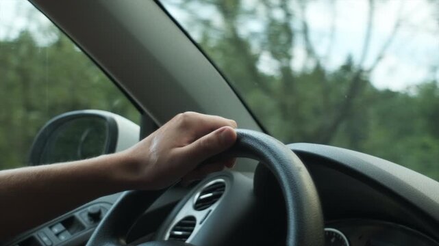 Close up of unknown young male drive camper van or delivery truck on winding mountain road between the trees near green forest at sunny day. Man drives car, hold hands on steering wheel. Slow motion