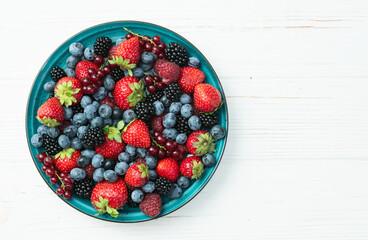 Mix of ripe colorful berries in bowl photography . Blueberry , strawberry , raspberry , blackberry and red currant . Top view