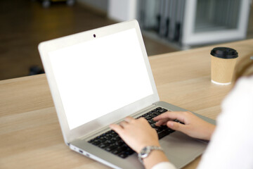 Fototapeta premium Back view of businesswoman sit at desk in office typing on laptop computer keyboard with white screen.