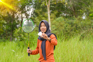 Adult Indonesian woman playing badminton in the park. Sporty urban Asian woman having fun in outdoor sports and summer activity concept games.