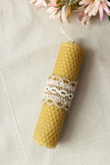 Handmade beautiful decorative candle of bee wax on pastel beige background.