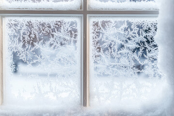 Delicate patterns of freshly fallen snow adorn a window pane, transforming the view into a winter wonderland of serene beauty.