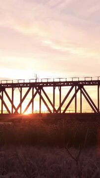 Panoramic view of train rides on rails through the bridge at sunrise. Timelapse. The train on the railway bridge