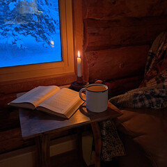 A cozy winter cabin scene with a mug, book, and candle.