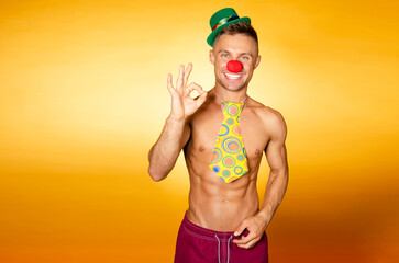 Handsome man in a clown costume. Orange background.