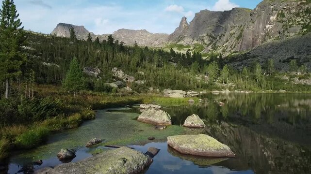Aerial view of rocky mountains peaks and lake from above. Scenic Lake surrounded by Mountains and trees. Ergaki national park. Beautiful Landscape. 
