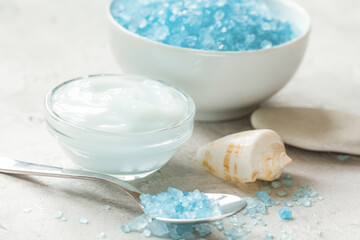 Home cosmetic with cream and blue sea salt on stone background