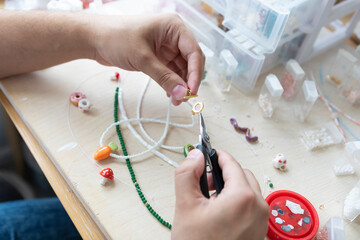 A creative man is engaged in beadwork. Hobby and small business concept	
