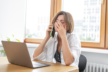 Shocked business woman looking at laptop and talking to mobile phone. She discussing problems in business	