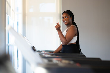 Obraz premium Portrait female jogging on treadmill. beautiful young chubby overweight african american woman wearing sporty fitness clothes doing exercise indoors at gym fitness sport club, body and health care
