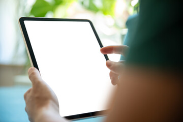 Person holding a tablet with a blank screen, in a bright, green environment. Perfect image for presenting tablet apps, user interfaces, or graphic designs.