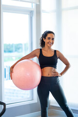 exercise yoga ball. beautiful young hispanic woman wearing sporty fitness clothes doing exercise indoors at gym fitness sport club, body and health care