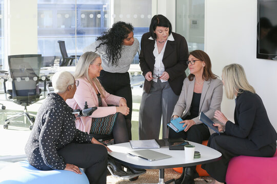 Businesswomen talking in office; Group of businesswomen, including disabled woman, having meeting in modern office