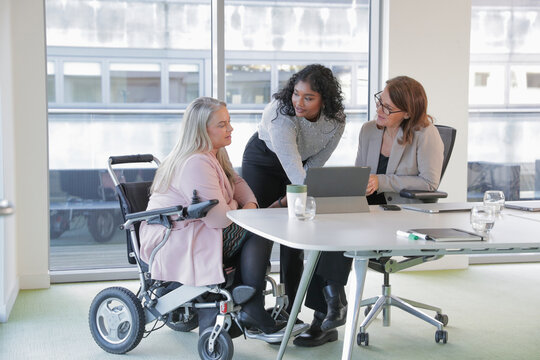 Businesswomen having meeting in office; Businesswomen, including 
disabled woman, talking during meeting in conference table in modern 
office