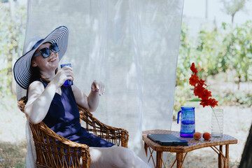 Portrait of a young woman with a glass of water sitting in the garden.