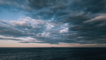 Lonely ship on the horizon, Evening dramatic sky with clouds, calm dark ocean