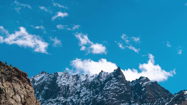 4K Zoom In time lapse of clouds moving over snow mountains at Jispa, Lahaul, India. Winter in Himalaya mountains. Nature background. Clouds moving over mountains in sunny day.