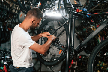 Fototapeta premium Focused at job. Repair man in bicycle shop, working in store
