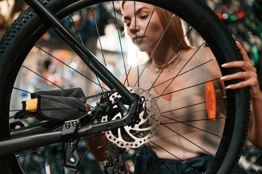 Taking care of the wheel. Repair woman in bicycle shop, working in store