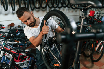 Final adjustments. Repair man in bicycle shop, working in store