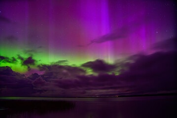 red green aurora borealis in lake with clouds