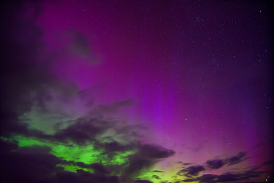 red green aurora borealis in lake with clouds