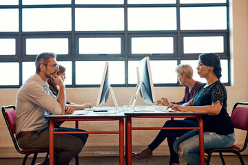 Happy, startup office and employees at desk, working together and communication on computer. Smile, project collaboration and coworking with people at web design studio with creative teamwork