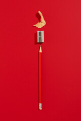 Red pencil with sharpener on a red background, top view