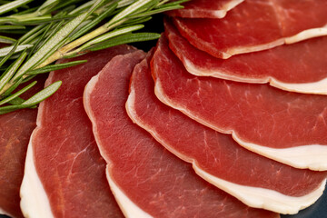 sliced ham with bacon on a board