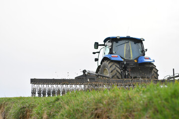 Back view of the tractor in the process of harrowing young cereal crops with a rotary harrow...
