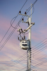 Transformer on high voltage pole with bright sky background.
