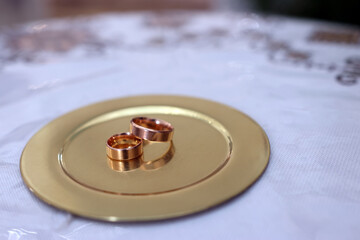 Golden wedding rings on a golden tray in the church.