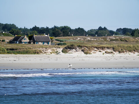 A surfer is walking by Pors Carn beach in French Brittany