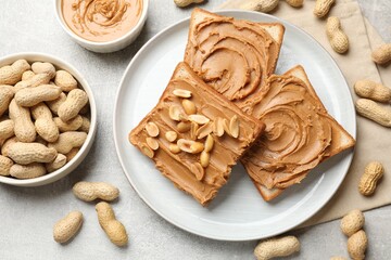 Tasty sandwiches with peanut butter and nuts on grey textured table, flat lay