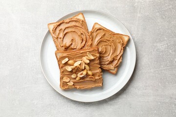 Tasty sandwiches with peanut butter and nuts on grey textured table, top view