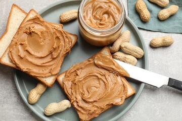 Tasty sandwiches with peanut butter and nuts on grey textured table, flat lay