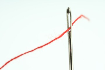 Sewing needle with red thread on white background, closeup