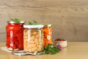 Different pickled products in jars and spices on wooden table