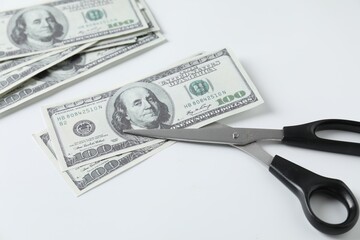 Budgeting. Dollar banknotes and scissors on white background, closeup
