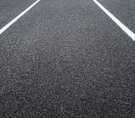 Track and Field Running Lane or Road Surface. Overhead view of a rubber black running track surface with white lane lines.