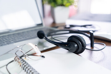 Headset, hotline support concept in office. VOIP headset on desk with laptop computer.