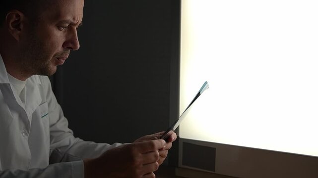 White doctor in a white coat. Doctor at night. Studying x-ray. Slow motion. High quality 4k footage.