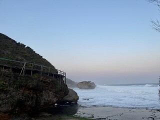 A rocky shoreline with a wooden boardwalk leading to the water