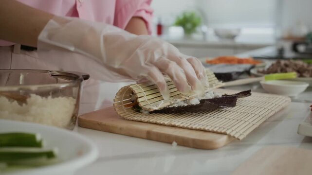 Cropped shot of hands of unrecognizable woman rolling gimbap on kitchen counter at home