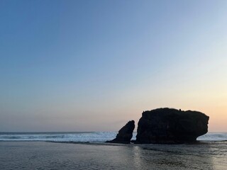 A rocky shoreline with a large rock in the foreground